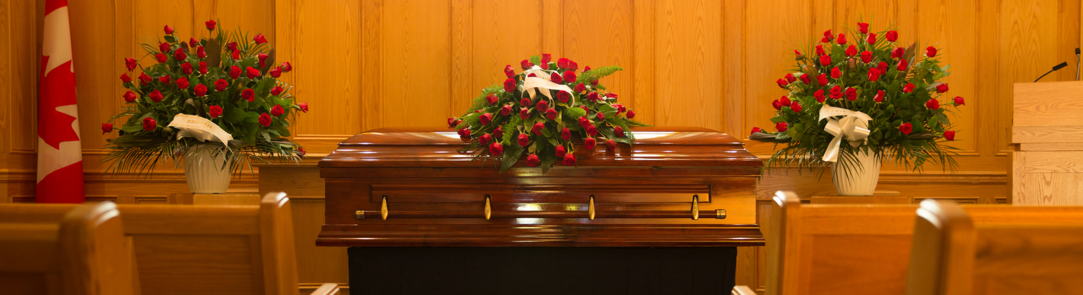 casket with red flowers atop and in background