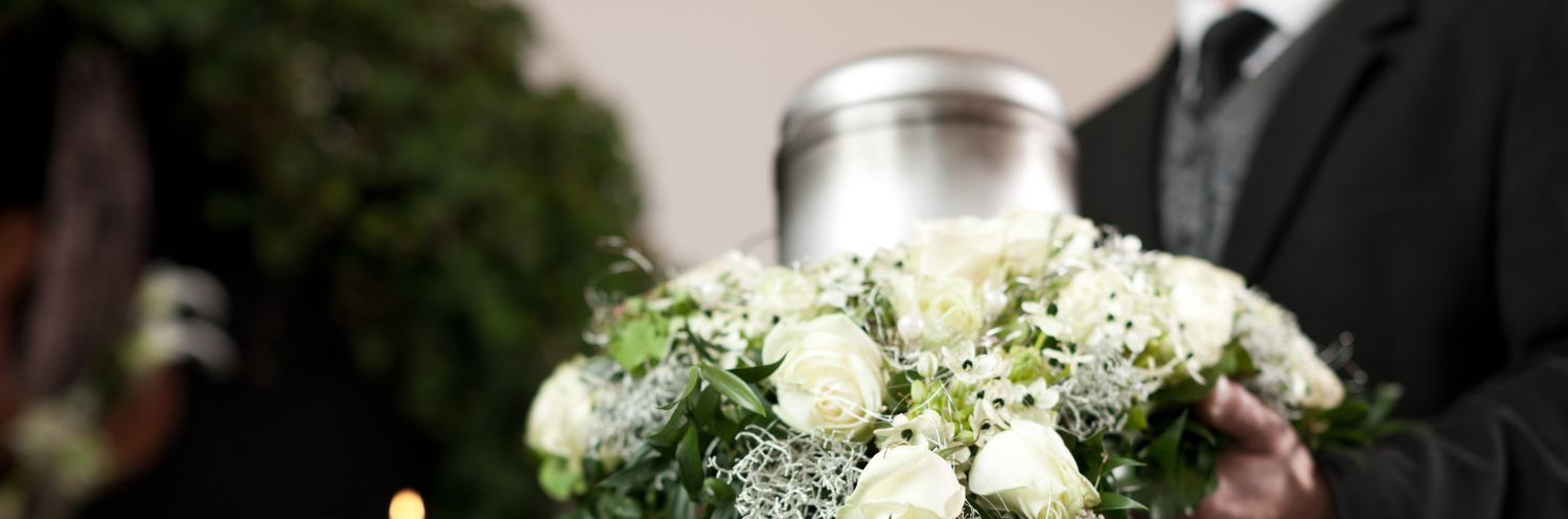 man holding white bouquet and urn