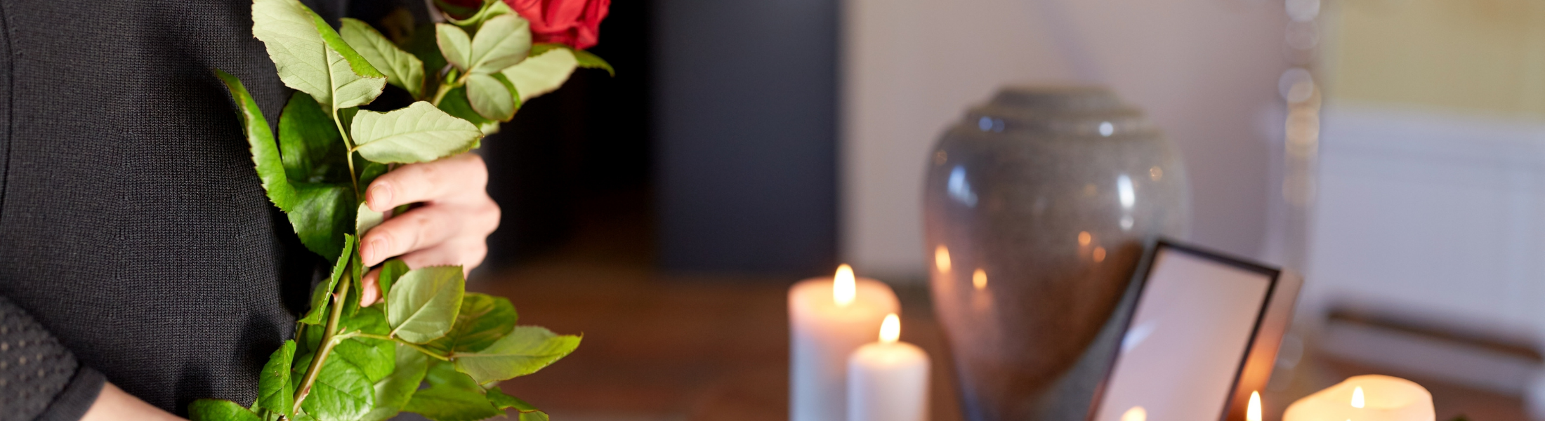 woman holding a rose standing in front of a cremation urn