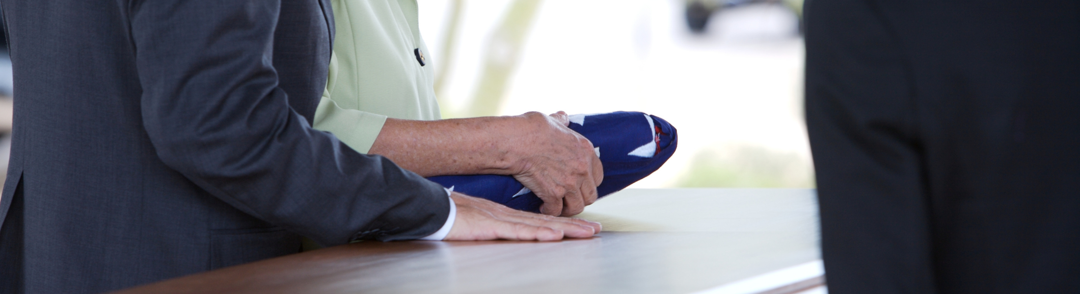 Person holding a folded flag over a casket